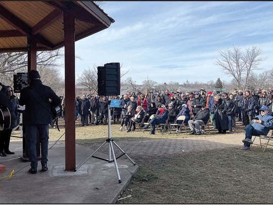 Above, event’s organizers initiated a collective singing of prayer songs. Below, protester Stacey Abenstein holds a sign that reads, “Hate has no home here.”